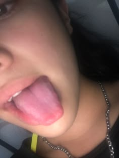 a woman sticking her tongue out in the back seat of a car while wearing a necklace