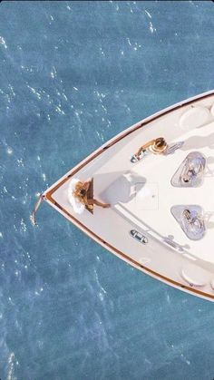 an aerial view of a white boat in the ocean with two people on it's deck