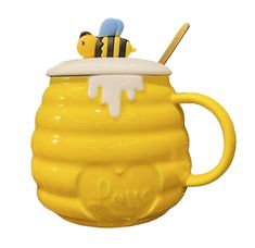 a yellow ceramic mug with a bee on top