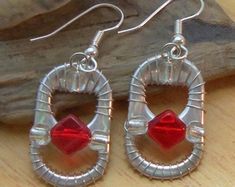 pair of silver and red earrings sitting on top of a wooden table