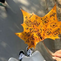 a person holding up a yellow leaf with writing on it's side and feet in the background