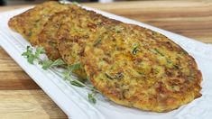 two crab cakes on a white plate with green garnish and sprigs