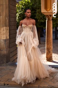 a model walks down the runway in an off - white gown with long sleeves and sheer tulle