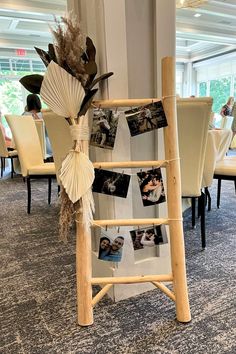 a wooden ladder with pictures hanging from it's sides in a room filled with tables and chairs