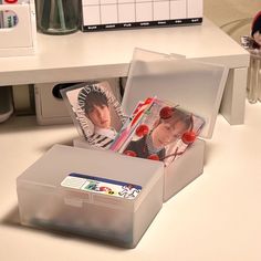 an open plastic box with photos in it on a white table next to other office supplies