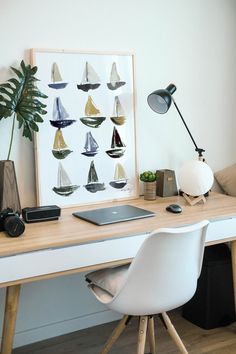 a white desk topped with a laptop computer next to a lamp and a potted plant