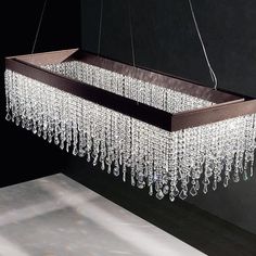 a rectangular chandelier hanging from a ceiling in a room with black walls and flooring