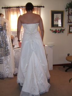 a woman in a wedding dress looking at herself