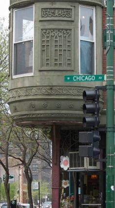 a traffic light sitting on the side of a road next to a tall green building