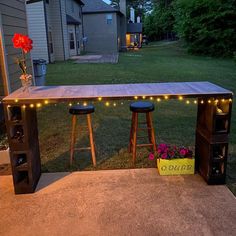 an outdoor bar with stools and lights on the outside, in front of a house