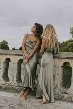 two women standing next to each other near water