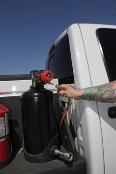 a man with tattoos on his arm is pumping gas into the back of a truck