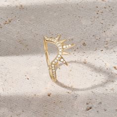 a gold ring with diamonds on it sitting on the ground in front of a white background