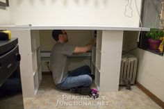 a man sitting on the floor in front of a white cabinet