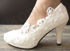 a woman's white high heeled shoes with pearls on the toes and heels