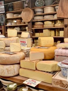 many different types of cheese are on display in a store with shelves full of other items