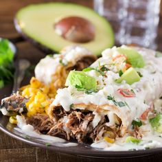 a close up of a plate of food with meat and vegetables next to an avocado