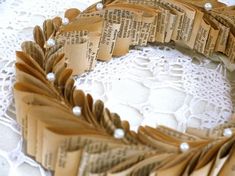 an old book page wreath is displayed on a doily