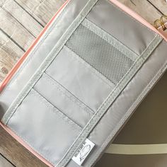 an open pink and grey purse sitting on top of a wooden floor