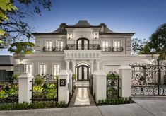 a large white house with wrought iron gates and gated entry way leading to the front entrance