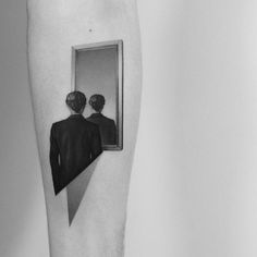 a black and white photo of two people looking in a mirror with one person's reflection