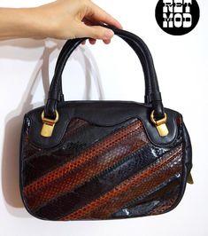 NWOT Chic Vintage 70s/80s Black Snakeskin Stripe Leather Top Handle Handbag Purse Please note that colors can vary from screen to screen, and in real life.  Brand new, 70s deadstock without store tags! Never used!! 10 x 7 x 3" with two 4.5" straps. Has a zip closure. Lined. Has an inner zip pocket, and a regular inside pocket on the other side. Gold-colored metal hardware. Has metal feet on bottom. I believe this is leather and real snakeskin. Marked: Morle Condition: 1 (brand new old 70s/80s stock) Condition Scale:  1-Immaculate Vintage Condition (Rare) 2-Unnoticeable Vintage Wear or Spots that are unphotographable 3-Small Noticeable Vintage Wear or Spots, as photographed 4-A Lot of Noticeable Vintage Wear or Spots, as photographed 5-Needs Repair or Work Top Handle Bags, Top Handle Handbags, Have Metal, Chic Vintage, Vintage Wear, Handbag Purse, Metal Hardware, Vintage Chic, Leather Top