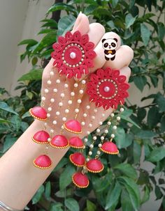 a hand with red and white jewelry on it