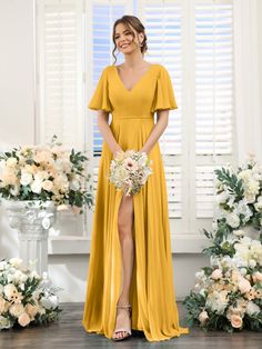 a woman standing in front of flowers wearing a yellow bridesmaid dress and holding a bouquet