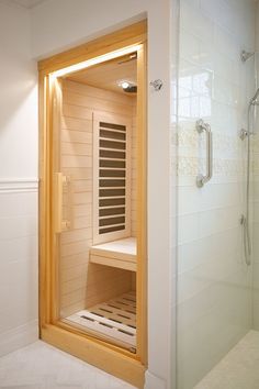 an empty sauna in a white bathroom next to a walk - in shower with glass doors