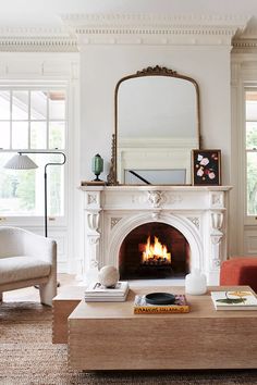 a living room filled with furniture and a fire place in front of a mirror on the wall