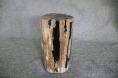 a wooden stool made out of logs on a gray surface with black spots in the wood