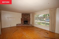 an empty living room with wood flooring and a brick fireplace in the middle of it