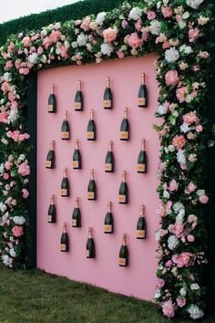 a pink wall with bottles of champagne on it and flowers all over the whole wall