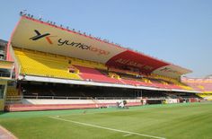 an empty soccer stadium with yellow and red seats