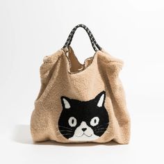 a black and white cat is on the side of a beige bag with chain handles