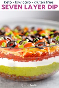 an image of a colorful layered dip with olives and peppers in it on a plate