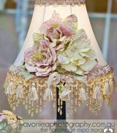 a lamp that has flowers on it and some beads hanging from the side of it