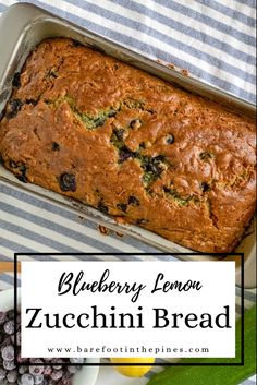 blueberry lemon zucchini bread in a loaf pan on a striped tablecloth