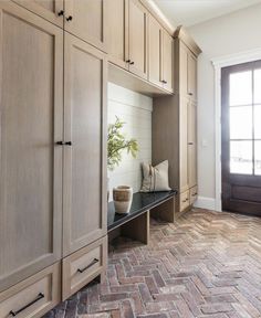 an entryway with built in cabinets and a potted plant sitting on the bench