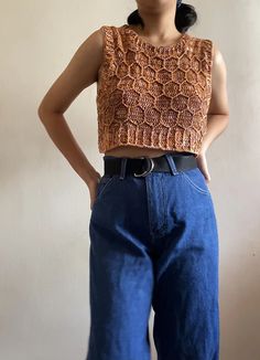 a woman standing in front of a wall wearing blue jeans and a cropped top