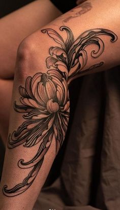 a woman's legs with tattoos on them and flowers in the middle of her leg