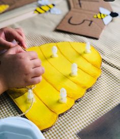 a child is decorating a yellow cake with white icing and bees on it