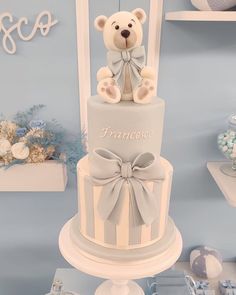 a three tiered cake with a teddy bear on top