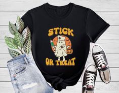 a black t - shirt that says stick or treat on it with a ghost and pumpkin