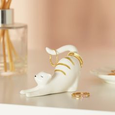 a white bear figurine sitting on top of a table next to two gold rings