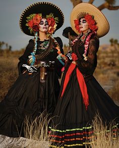 two women dressed in mexican style clothing standing next to each other wearing hats and dresses