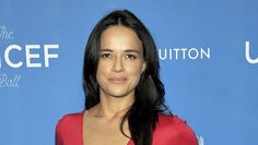 a woman in a red dress posing for the camera with her long hair pulled back