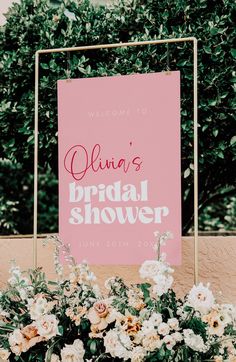 a pink sign with white flowers and greenery in front of it that says julia's bridal shower