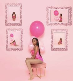 a woman sitting on top of a stool in front of pink wall with balloons and pictures