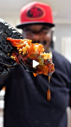 a man is holding up a piece of food that has been drizzled with sauce